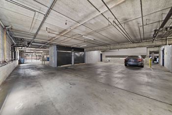 A car is parked in a large, empty parking garage.